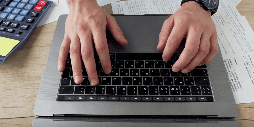 Hands typing on a laptop while working on technical and sales tasks.